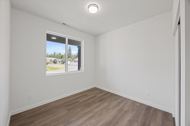 empty room with visible vents, baseboards, and wood finished floors