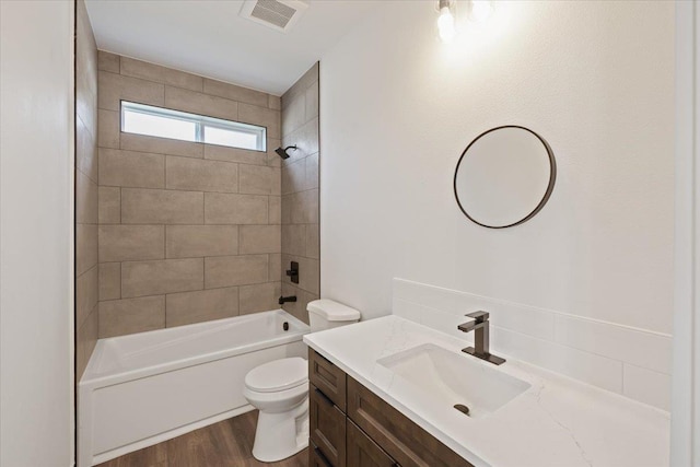 bathroom featuring visible vents, toilet, wood finished floors, bathtub / shower combination, and vanity