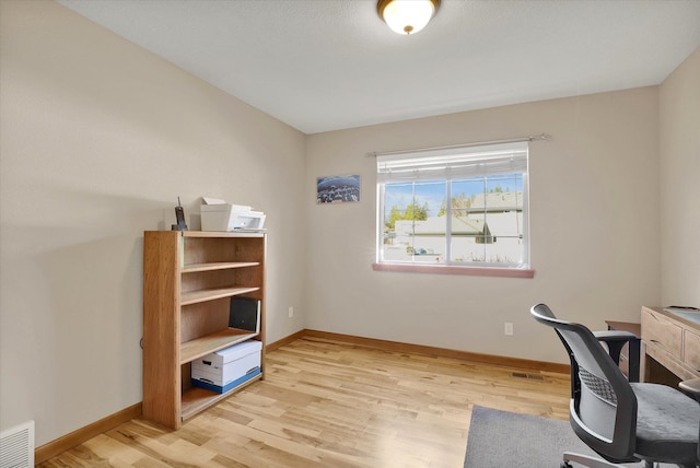 office area with light wood finished floors, visible vents, and baseboards