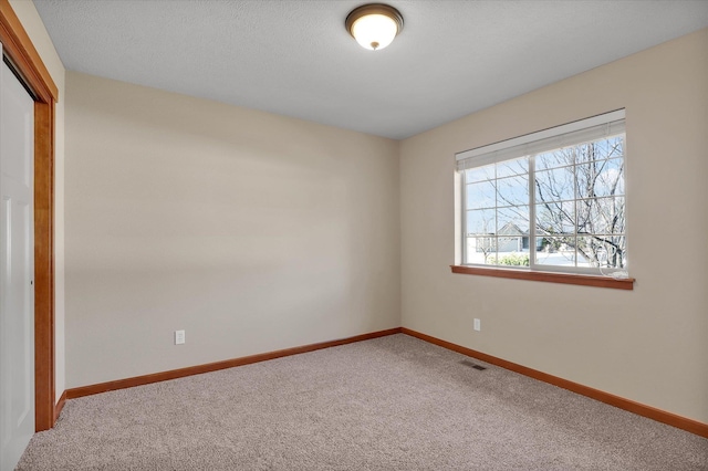 carpeted empty room featuring baseboards and visible vents