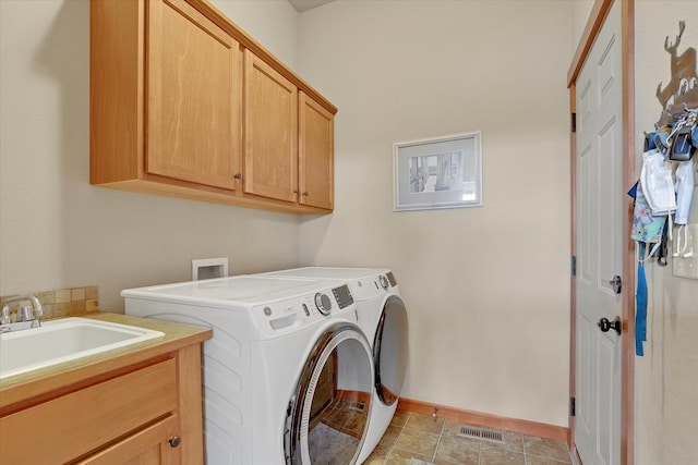 washroom with baseboards, visible vents, cabinet space, a sink, and washer and dryer