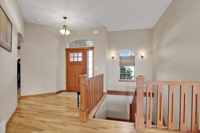 foyer with visible vents, arched walkways, baseboards, and light wood finished floors