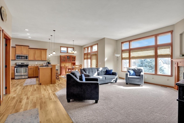 living area with light wood finished floors, visible vents, baseboards, recessed lighting, and an inviting chandelier