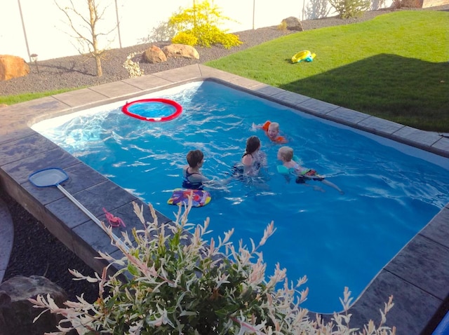 view of swimming pool with a lawn and fence