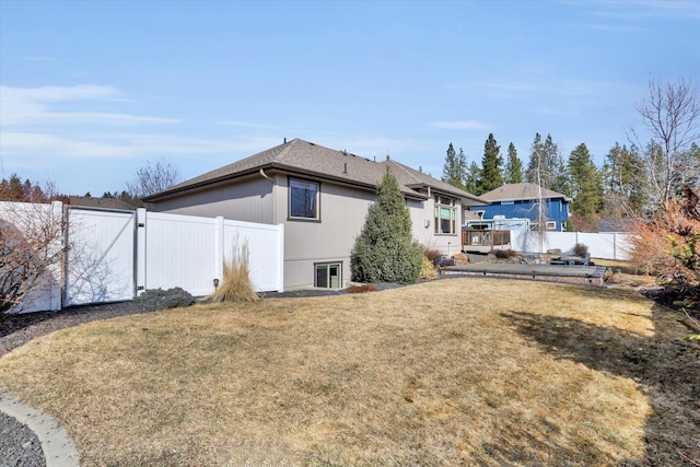 back of property featuring a gate, a fenced backyard, a lawn, and a shingled roof