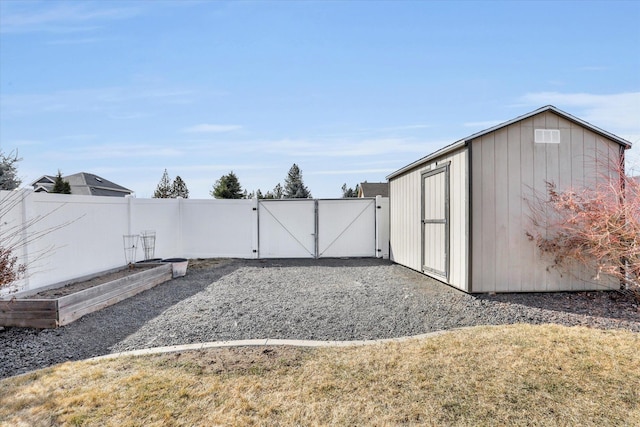 view of yard featuring fence, a storage shed, an outdoor structure, a vegetable garden, and a gate