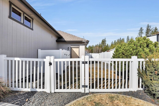 view of home's exterior featuring a gate, fence, and roof with shingles