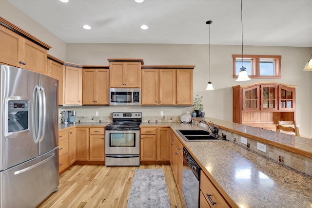 kitchen featuring light wood finished floors, light brown cabinetry, light countertops, appliances with stainless steel finishes, and a sink