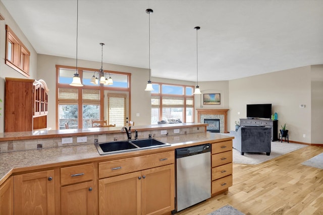 kitchen with stainless steel dishwasher, decorative light fixtures, light wood-style floors, and a sink