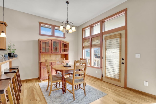 dining room with light wood finished floors, a notable chandelier, and baseboards