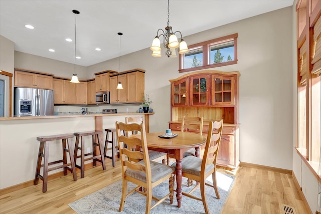 dining room featuring baseboards, visible vents, light wood-type flooring, and a chandelier