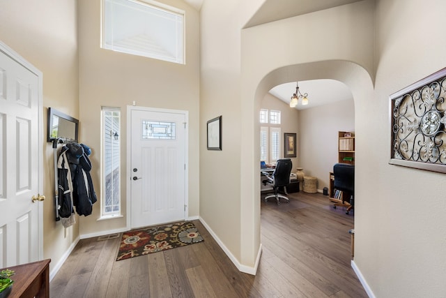 entrance foyer featuring hardwood / wood-style floors, arched walkways, and a towering ceiling