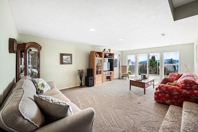 carpeted living area with visible vents, recessed lighting, a textured ceiling, and baseboards