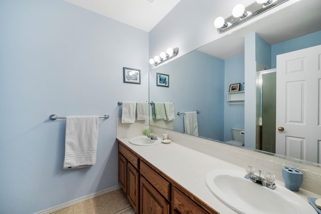 full bathroom with a shower stall, double vanity, baseboards, and a sink