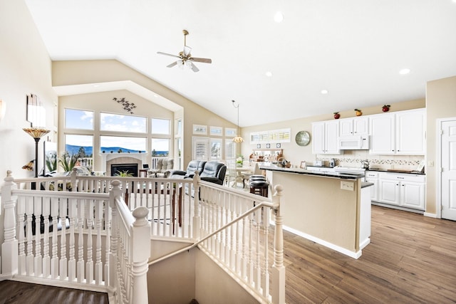 staircase featuring wood finished floors, recessed lighting, a fireplace, ceiling fan, and vaulted ceiling