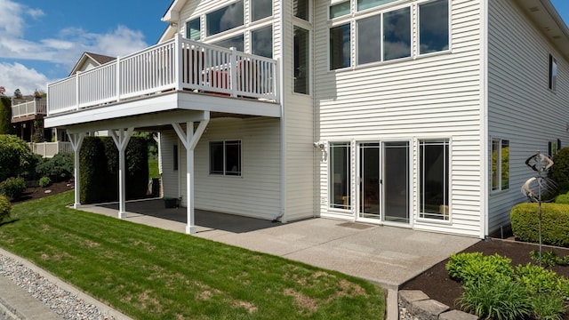 back of property with a deck, a patio, and a lawn