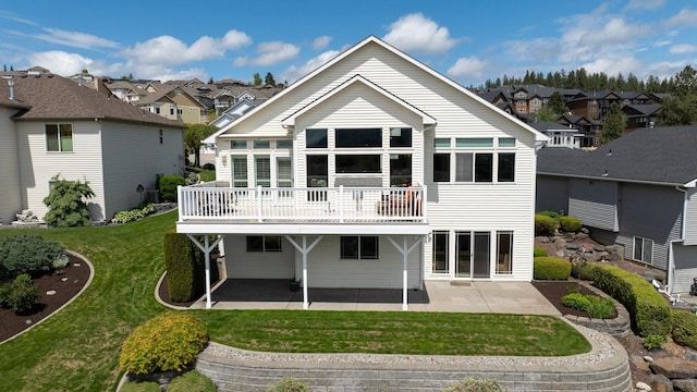 rear view of property featuring a patio, a lawn, and a residential view