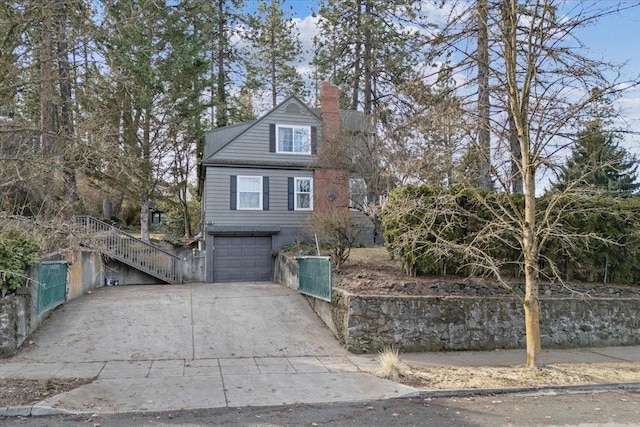 view of front of property featuring stairway, driveway, a chimney, and a garage