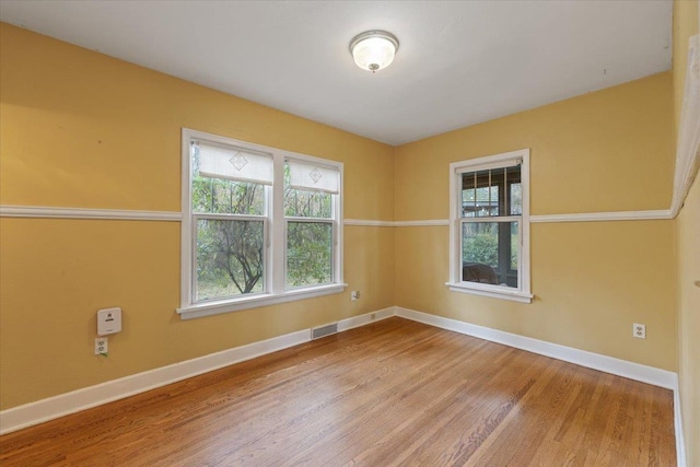 unfurnished room featuring visible vents, baseboards, and wood finished floors