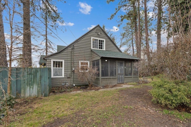 rear view of house with fence, a sunroom, and a shingled roof