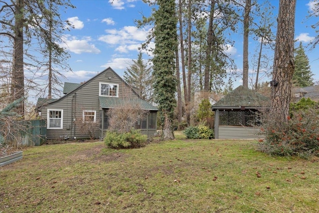 rear view of house featuring a yard and a sunroom