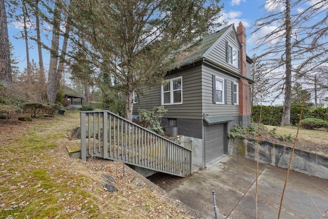 back of house featuring driveway, a chimney, and a garage