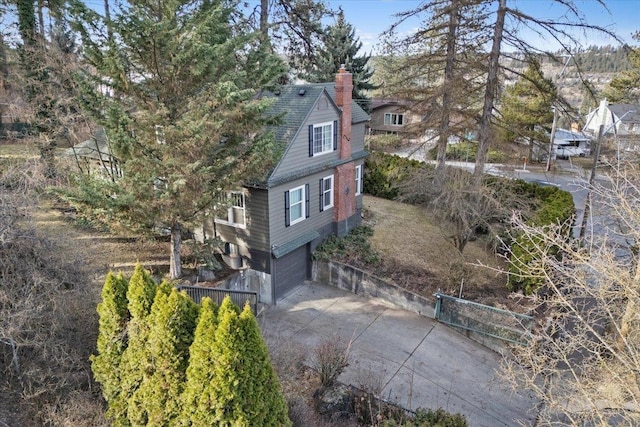 exterior space with a chimney, an attached garage, and concrete driveway