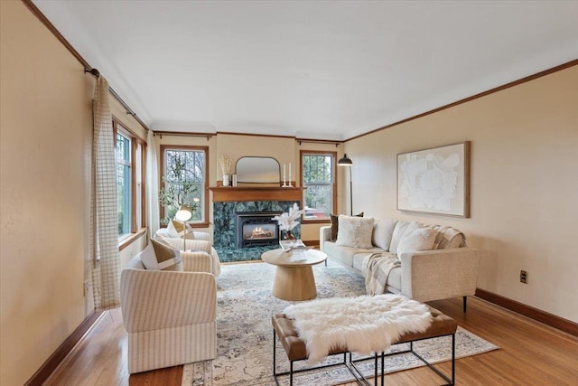 living area featuring a healthy amount of sunlight, a fireplace, ornamental molding, and wood finished floors