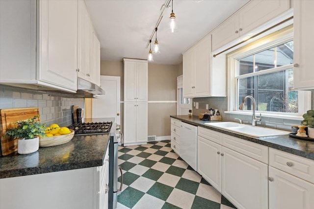 kitchen with stainless steel gas range oven, dark countertops, light floors, white dishwasher, and a sink