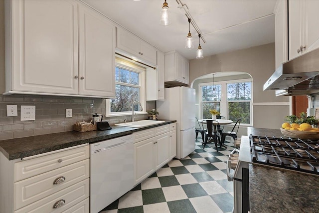 kitchen featuring white appliances, light floors, arched walkways, a sink, and white cabinetry