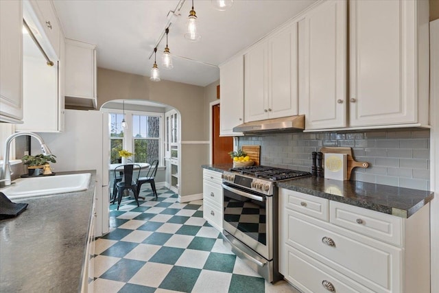 kitchen with under cabinet range hood, gas range, arched walkways, tile patterned floors, and a sink