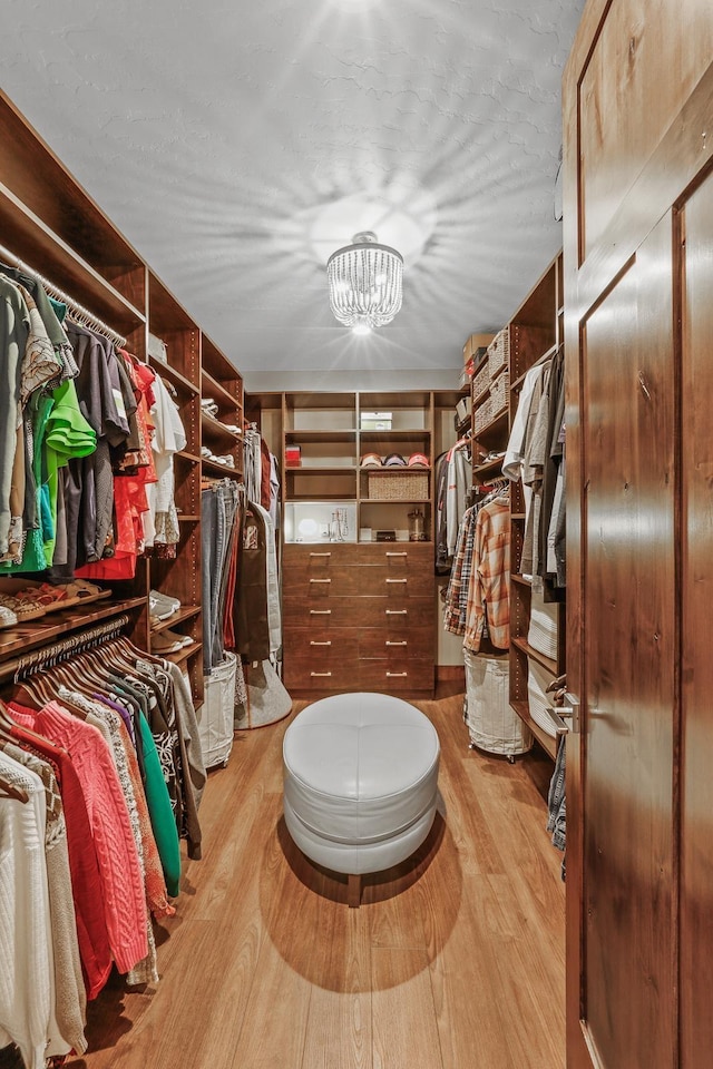 walk in closet with a notable chandelier and light wood-style floors