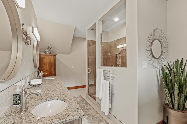 bathroom with a sink, baseboards, walk in shower, and double vanity