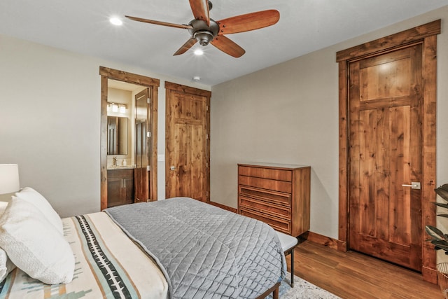 bedroom featuring baseboards, recessed lighting, ensuite bathroom, wood finished floors, and a ceiling fan