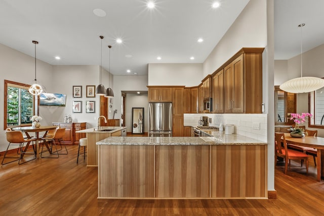 kitchen featuring brown cabinets, appliances with stainless steel finishes, a peninsula, and a sink