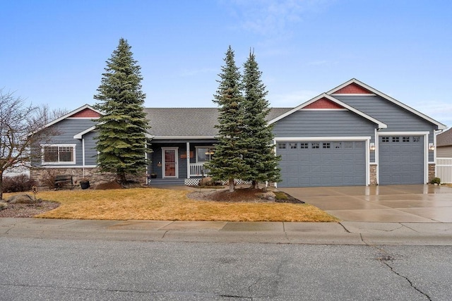 view of front of home featuring a porch, stone siding, an attached garage, and driveway