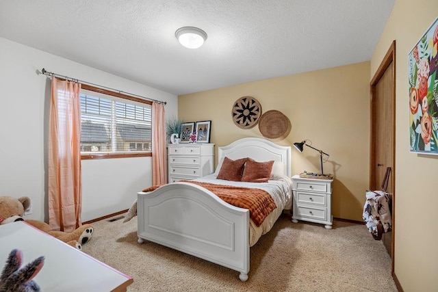 bedroom with light colored carpet, a textured ceiling, and baseboards