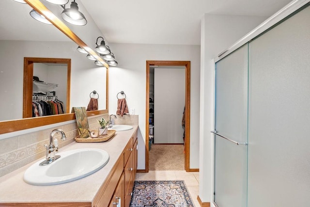 full bathroom featuring tile patterned flooring, a stall shower, a walk in closet, and a sink