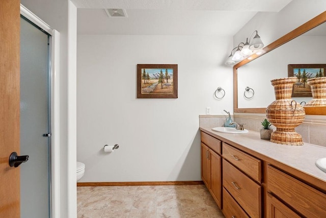 full bath with visible vents, baseboards, double vanity, an enclosed shower, and a sink