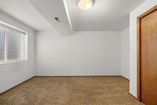 carpeted spare room with visible vents, a textured ceiling, and baseboards