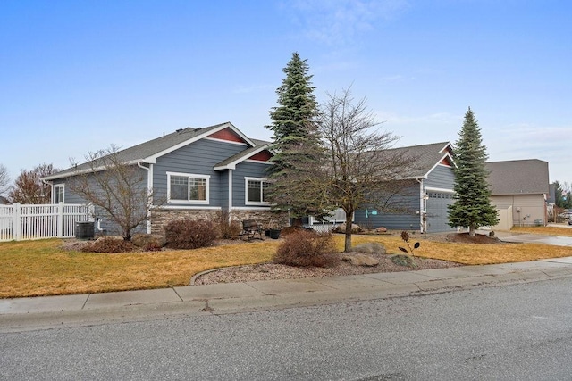 view of front of house featuring fence, central air condition unit, a garage, stone siding, and driveway