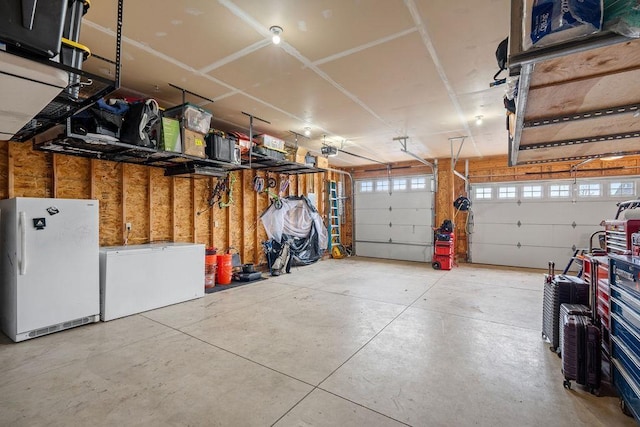 garage featuring refrigerator, freestanding refrigerator, and a garage door opener