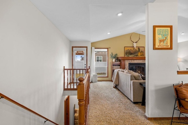 carpeted living area with a glass covered fireplace and vaulted ceiling