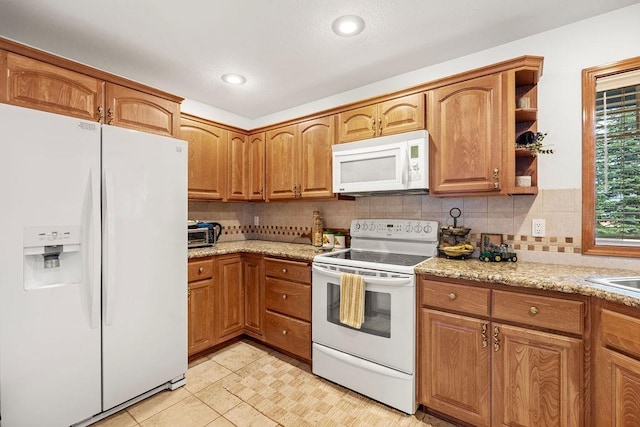 kitchen with brown cabinets, open shelves, tasteful backsplash, white appliances, and light stone countertops