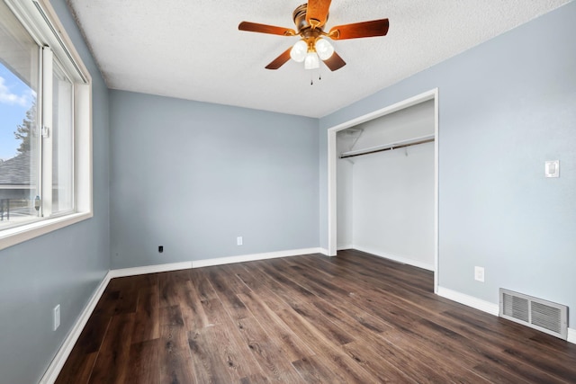 unfurnished bedroom featuring visible vents, a textured ceiling, wood finished floors, a closet, and baseboards