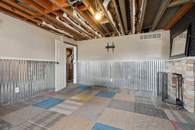 basement with a fireplace with raised hearth, visible vents, and carpet floors