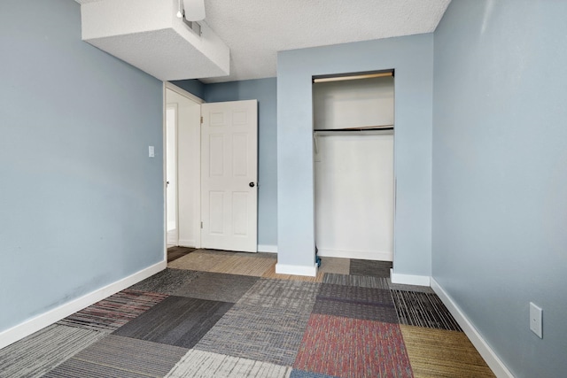 unfurnished bedroom featuring carpet, baseboards, a closet, and a textured ceiling