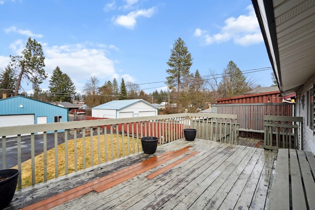 wooden deck with an outbuilding, a lawn, and a detached garage