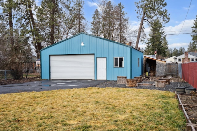 detached garage featuring aphalt driveway and fence