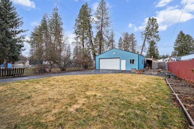 view of yard featuring an outbuilding, fence, driveway, and a detached garage